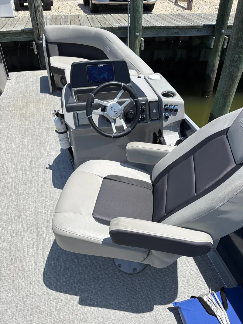 Slide: The Image of 2024 Harris Cruiser 230 boat interior with steering wheel and seating at dock. - 3