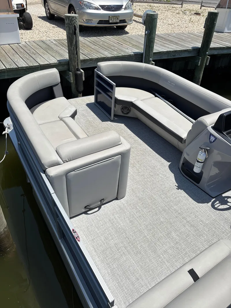 Slide: The Image of 2024 Harris Cruiser 230 pontoon boat with spacious seating, docked at a marina. - 5