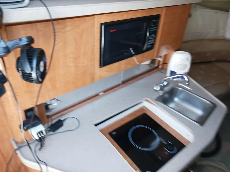 Slide: The Image of 2004 Regal 2760 Commodore boat interior with kitchenette, sink, and microwave. - 12