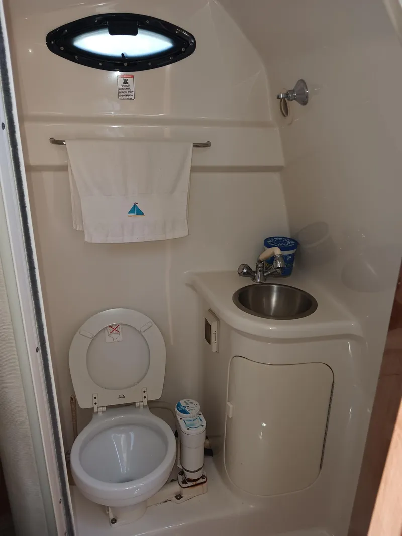 Slide: The Image of Compact bathroom in a 2004 Regal 2760 Commodore boat, featuring a toilet and sink. - 16