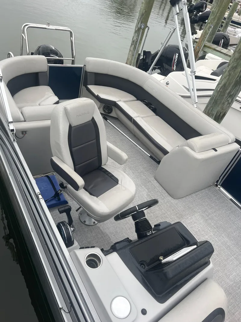 Slide: The Image of 2024 Harris Cruiser 230 boat interior with plush seating and steering console. - 10
