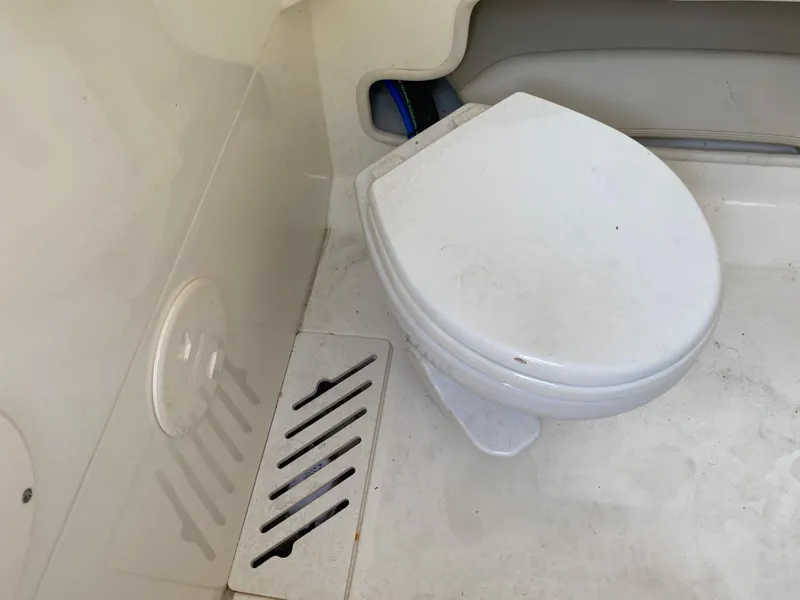 Slide: The Image of 2022 Boston Whaler 250 Outrage boat toilet area with white marine toilet and floor vent. - 17
