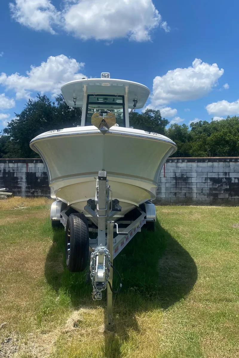 Slide: The Image of 2022 Boston Whaler 250 Outrage boat on trailer, parked on grass under a blue sky. - 3