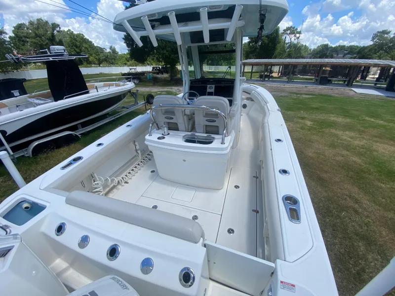 Slide: The Image of 2022 Boston Whaler 250 Outrage boat interior with seating and console, parked outdoors. - 8