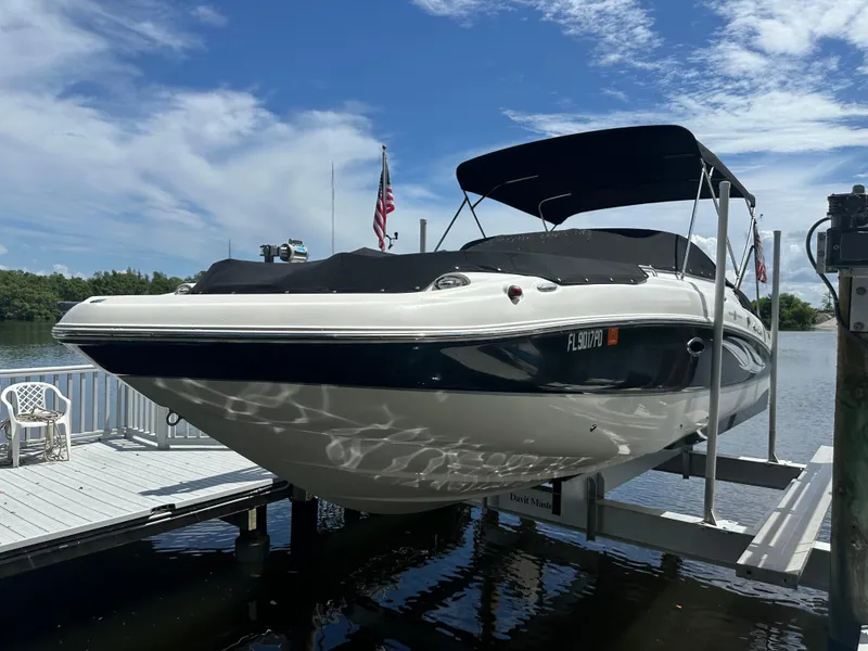 The Image of 2011 Sea Ray 240 Sundeck boat docked, featuring a sleek design and black canopy. - 0