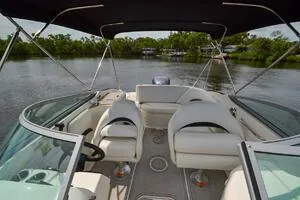 Slide: The Image of 2011 Sea Ray 240 Sundeck boat interior with seating, on a calm lake. - 10
