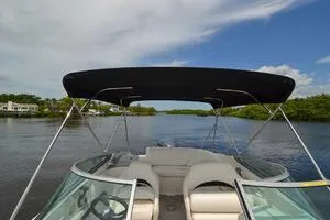 Slide: The Image of 2011 Sea Ray 240 Sundeck boat with canopy on a calm river under blue sky. - 11