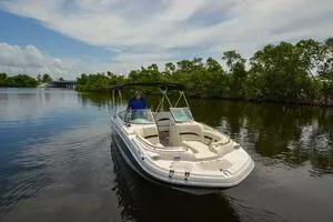 Slide: The Image of 2011 Sea Ray 240 Sundeck boat cruising on a calm river with lush greenery. - 5
