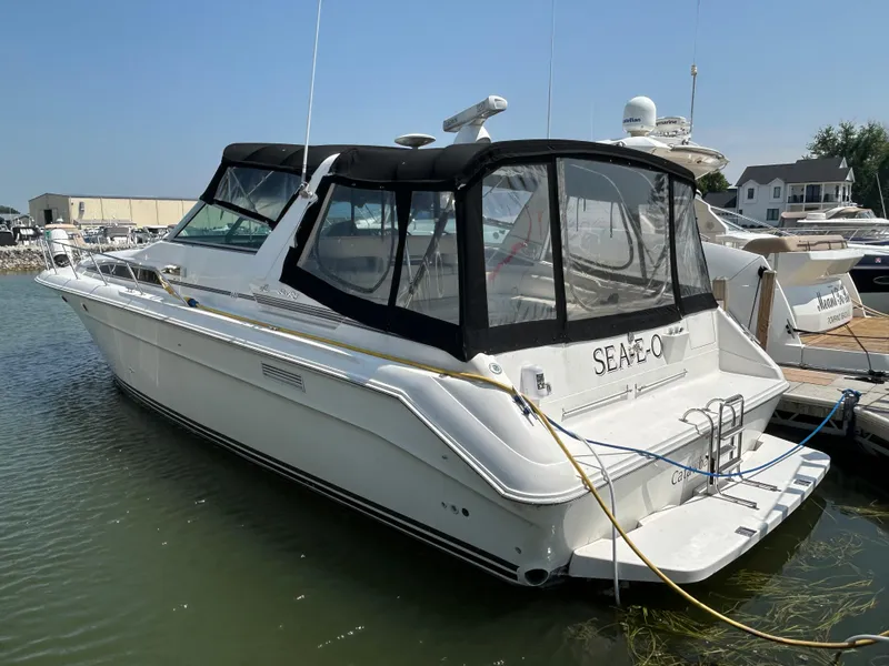 The Image of 1993 Sea Ray 440 Sundancer yacht docked at marina, featuring sleek design and black canopy. - 0