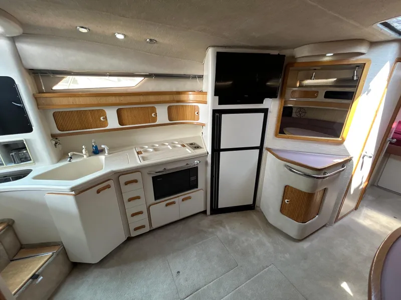 Slide: The Image of 1993 Sea Ray 440 Sundancer kitchen area with refrigerator. - 48