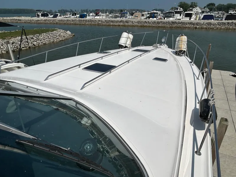 Slide: The Image of 1993 Sea Ray 440 Sundancer yacht docked at a marina, showcasing its sleek deck design. - 8