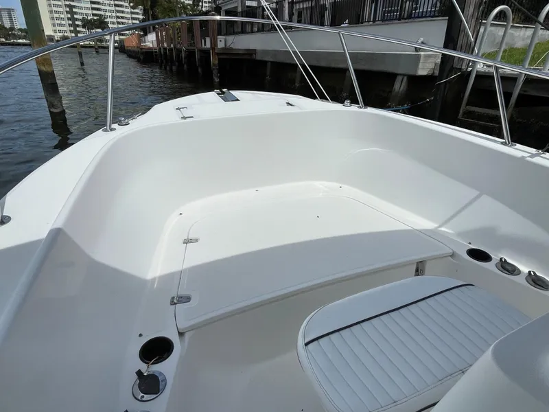Slide: The Image of 1999 Boston Whaler Outrage 23 boat interior, featuring white seating and railings by the water. - 8