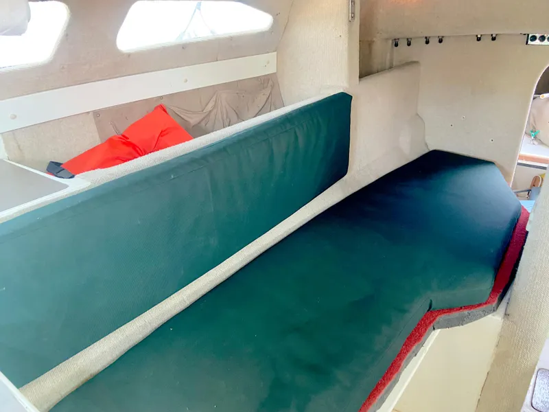 Slide: The Image of Interior of 1990 Corsair F27 sailboat with green cushions and red pillow. - 15