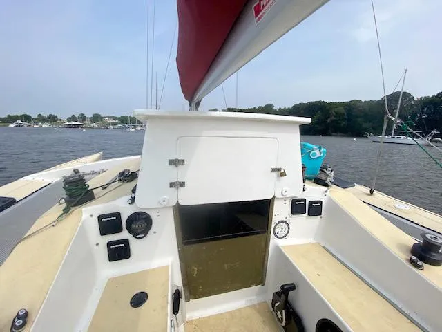 Slide: The Image of Cockpit view of 1990 Corsair F27 sailboat on calm water, featuring control panels and seating. - 6