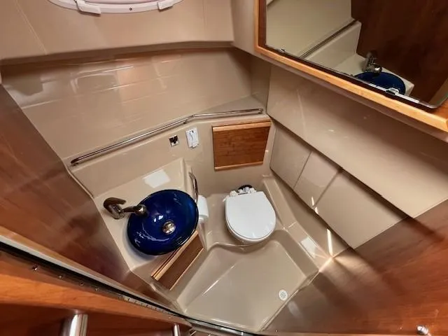 Slide: The Image of 2016 Cutwater 26 boat bathroom with blue sink, toilet, and wooden accents. - 15