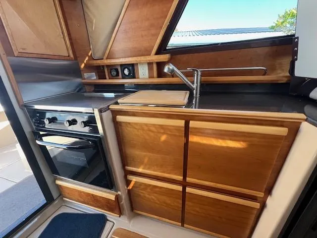 Slide: The Image of Compact kitchen in a 2016 Cutwater 26 boat, featuring wood cabinetry and stainless steel appliances. - 7