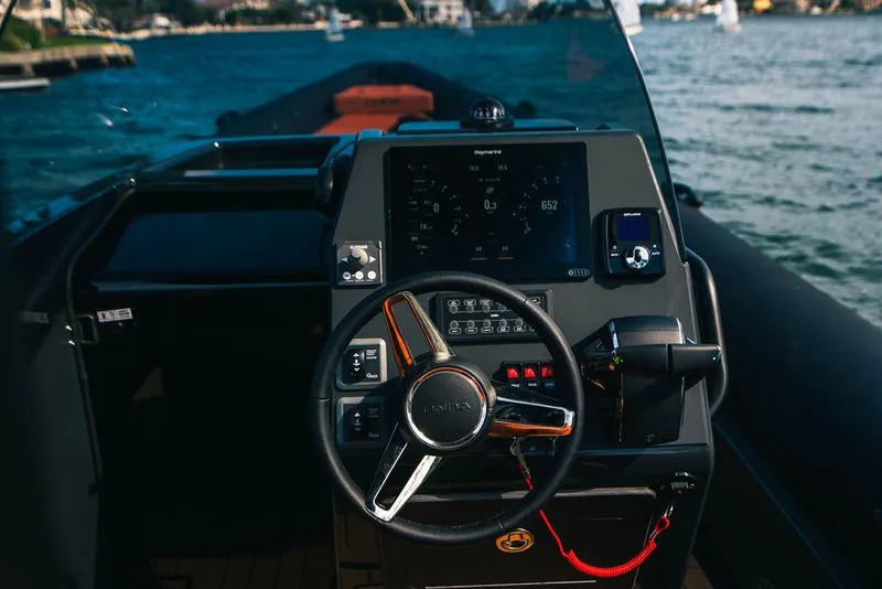 Slide: The Image of Steering console of 2025 Onda Magna boat with digital display, on a scenic waterway. - 11
