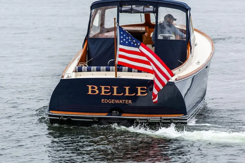 Slide: The Image of 1998 Hinckley Picnic Boat "Belle" with American flag on water. - 13