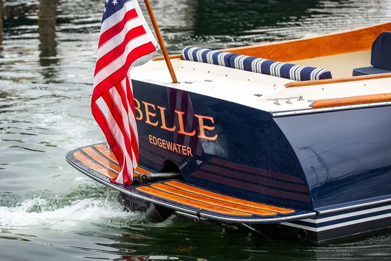 Slide: The Image of Hinckley Picnic Boat 1998 with American flag, named "Belle," docked in water. - 14