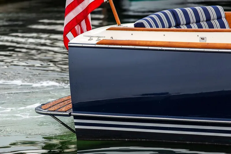 Slide: The Image of 1998 Hinckley Picnic Boat with American flag and striped seating on water. - 16