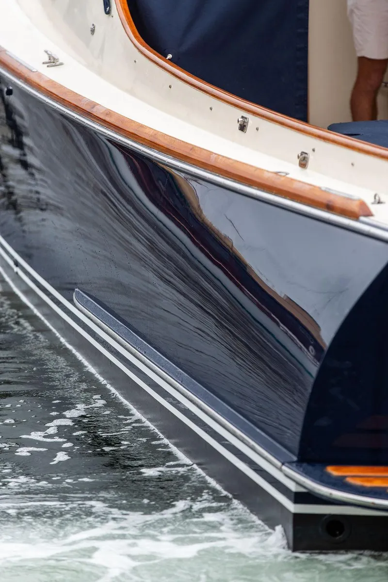 Slide: The Image of 1998 Hinckley Picnic Boat with sleek navy hull on water. - 18