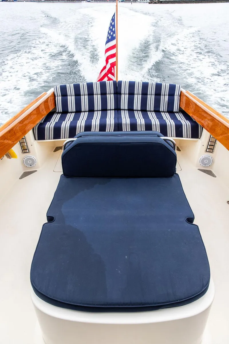 Slide: The Image of 1998 Hinckley Picnic Boat with striped seating and American flag, cruising on water. - 21