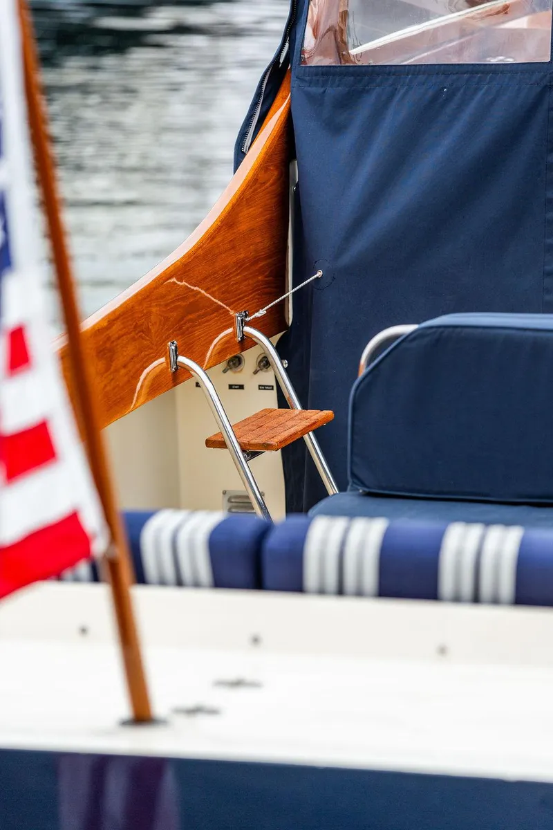 Slide: The Image of 1998 Hinckley Picnic Boat with blue upholstery and American flag detail. - 26