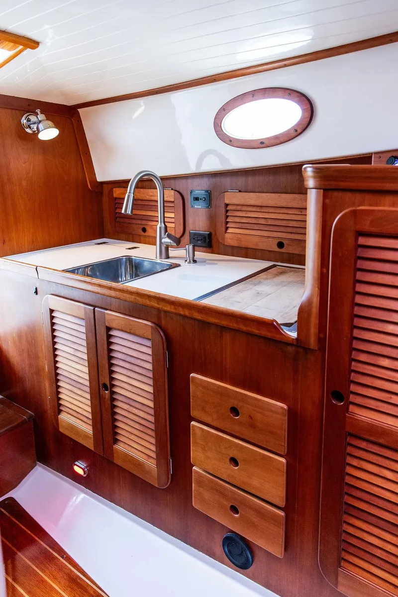 Slide: The Image of 1998 Hinckley Picnic Boat interior with wooden cabinetry and stainless steel sink. - 33