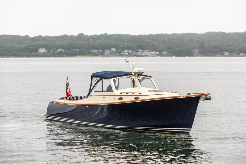 Slide: The Image of 1998 Hinckley Picnic Boat on calm water, featuring classic design and American flag. - 9