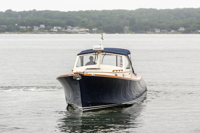 Slide: The Image of 1998 Hinckley Picnic Boat cruising on calm waters with forested shoreline in background. - 12