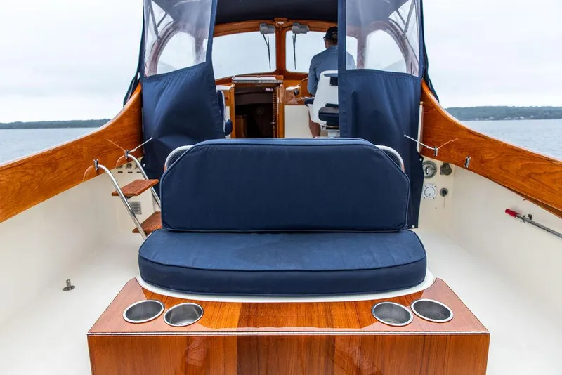 Slide: The Image of 1998 Hinckley Picnic Boat interior with blue seating and wooden accents on a calm water backdrop. - 22