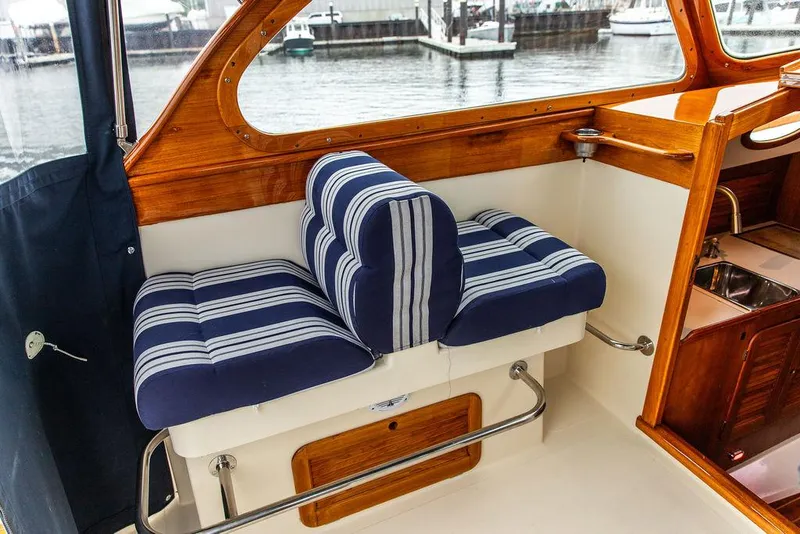 Slide: The Image of 1998 Hinckley Picnic Boat interior with striped blue seating and wooden accents. - 24