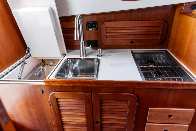 Slide: The Image of 1998 Hinckley Picnic Boat galley with sink, stove, and wooden cabinetry. - 32