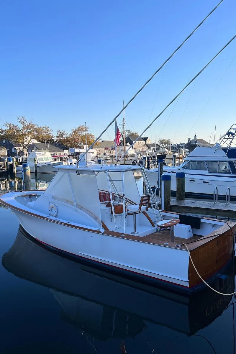The Image of 1985 Rybovich 32 Express Walkaround Sportfish docked in a marina under clear blue sky. - 1