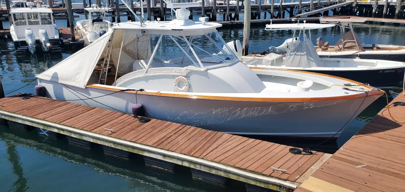 Slide: The Image of 1985 Rybovich 32 Express Walkaround Sportfish docked at marina, featuring sleek design and wooden accents. - 11