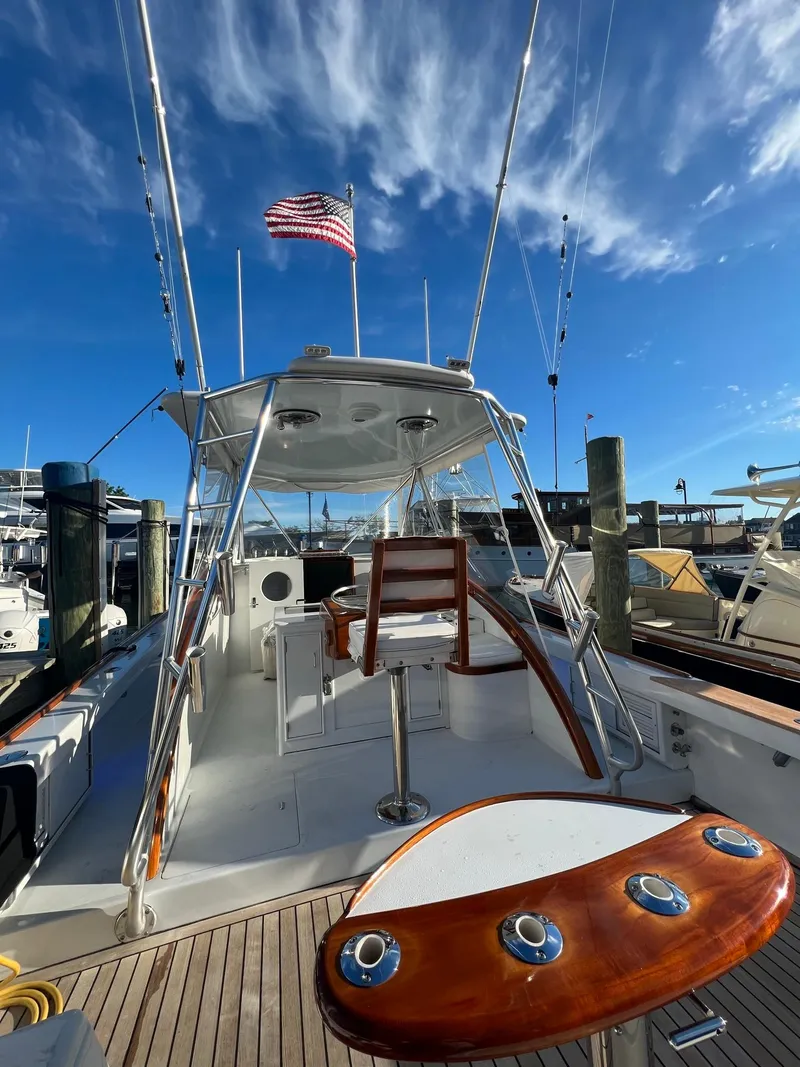 Slide: The Image of 1985 Rybovich 32 Express Walkaround Sportfish boat with American flag, docked under blue sky. - 14