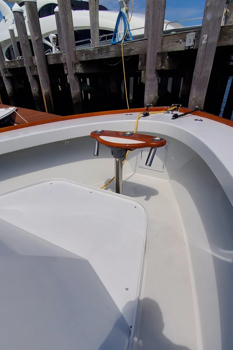 Slide: The Image of 1985 Rybovich 32 Express Walkaround Sportfish boat interior with wooden accents and dock view. - 17