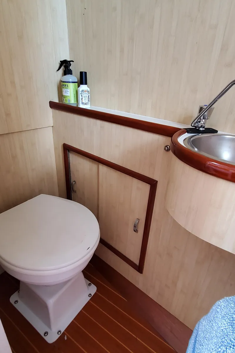 Slide: The Image of 1985 Rybovich 32 Express Walkaround Sportfish bathroom with toilet, sink, and cleaning supplies. - 19
