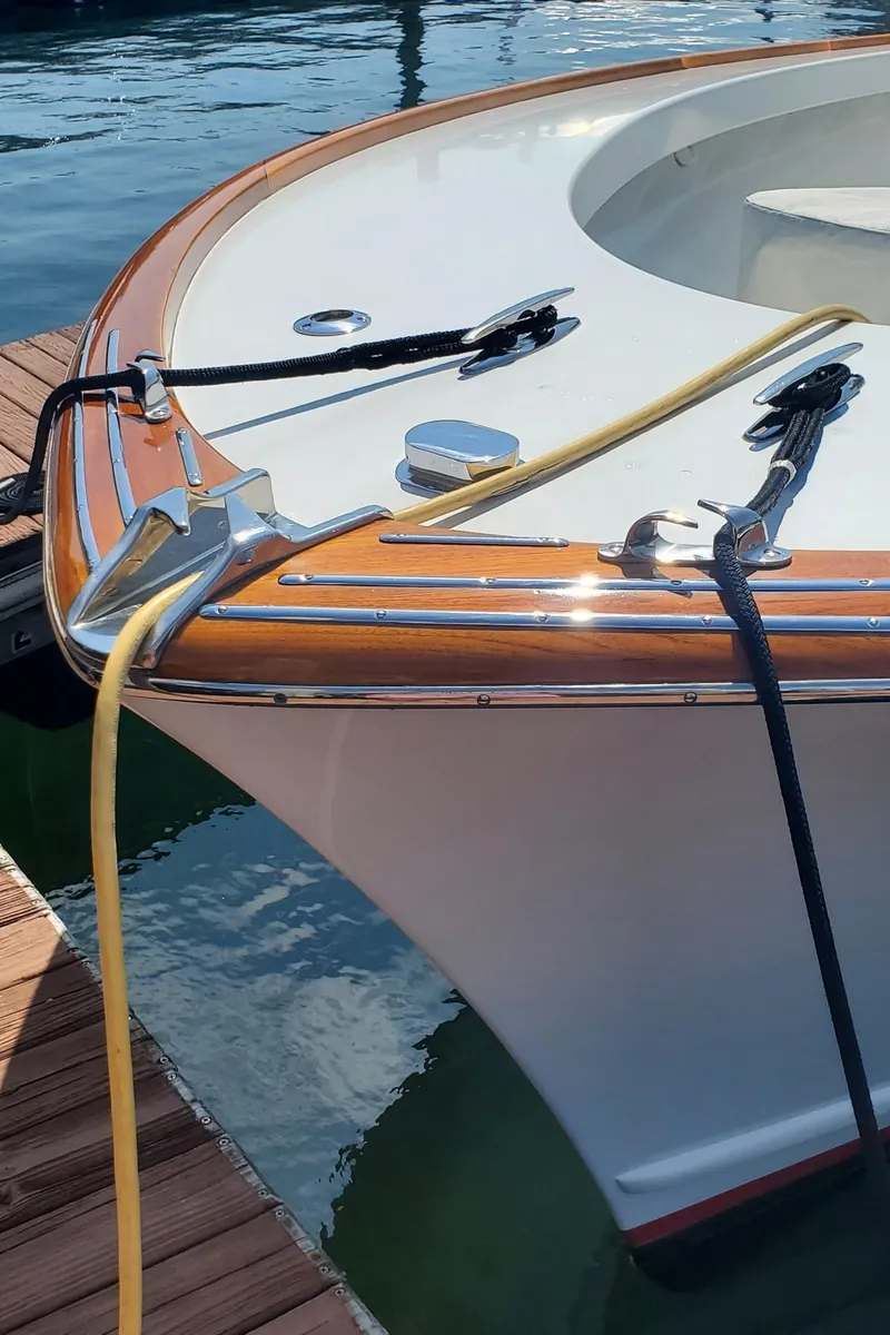 Slide: The Image of 1985 Rybovich 32 Express Walkaround Sportfish boat docked, featuring polished wood and sleek design. - 5