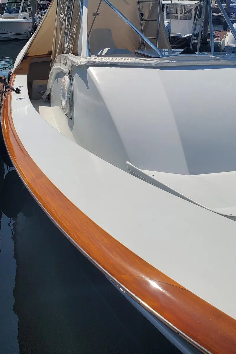 Slide: The Image of 1985 Rybovich 32 Express Walkaround Sportfish boat with sleek white hull and wooden trim. - 7
