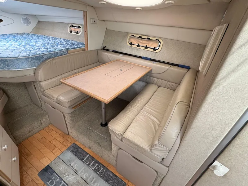 Slide: The Image of 1997 Maxum 3200 SCR interior with beige seating, wooden table, and cozy sleeping area. - 12