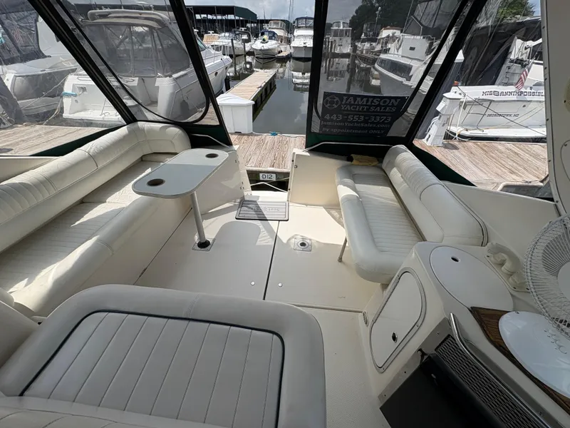 Slide: The Image of 1997 Maxum 3200 SCR yacht interior with white seating and table, docked at marina. - 20