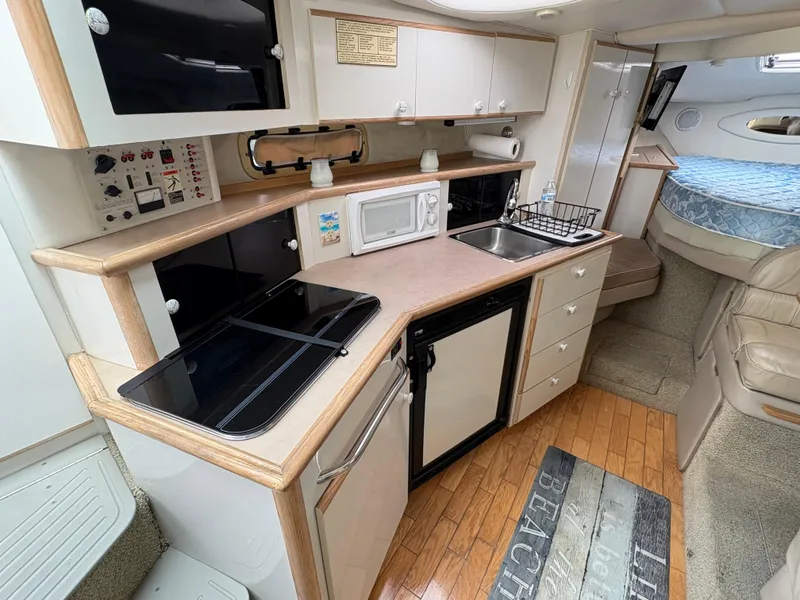 Slide: The Image of 1997 Maxum 3200 SCR boat interior with kitchenette, microwave, sink, and cozy sleeping area. - 8