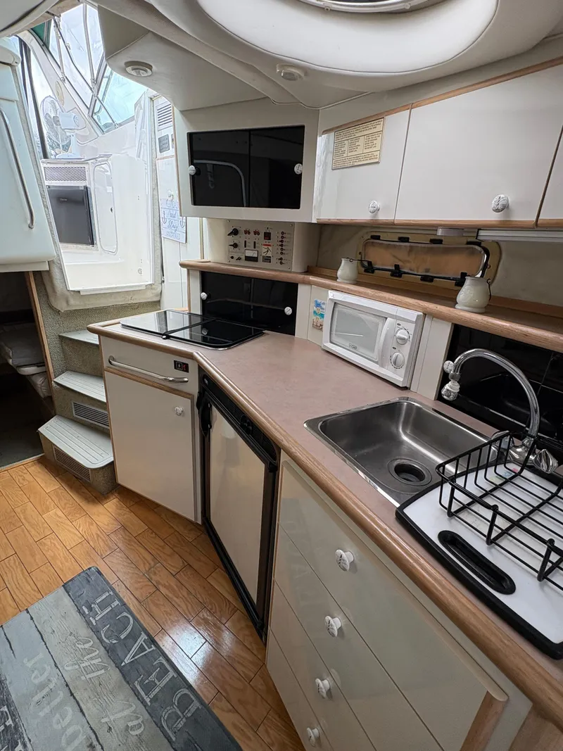 Slide: The Image of 1997 Maxum 3200 SCR boat kitchen with stove, microwave, sink, and wooden flooring. - 9