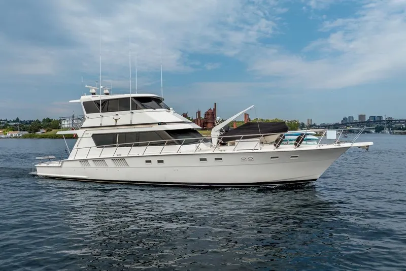The Image of 1988 Hatteras 65 Sportfish yacht cruising on a calm waterway under a blue sky. - 0