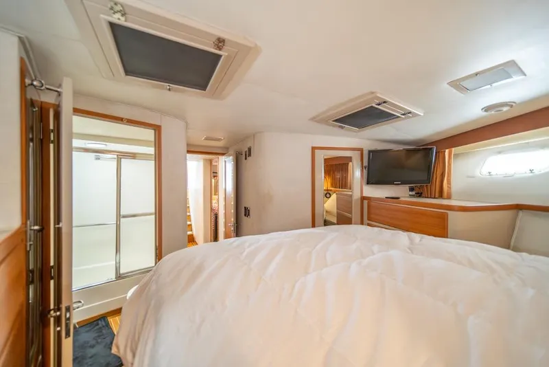 Slide: The Image of Luxurious bedroom interior of 1988 Hatteras 65 Sportfish yacht with TV and ensuite bathroom. - 21