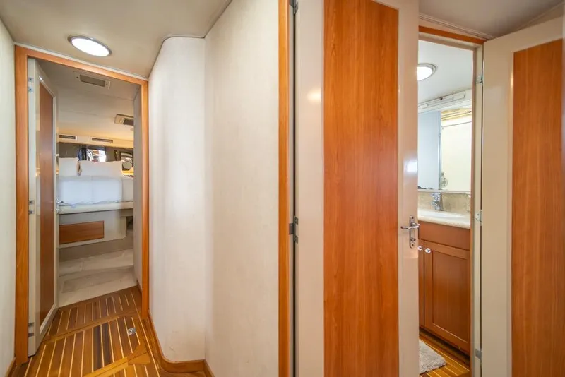 Slide: The Image of Hallway view inside 1988 Hatteras 65 Sportfish yacht, featuring wood paneling and cabin access. - 26