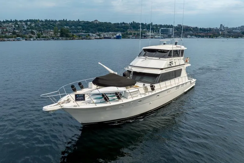 Slide: The Image of 1988 Hatteras 65 Sportfish yacht cruising on a calm lake with cityscape background. - 3