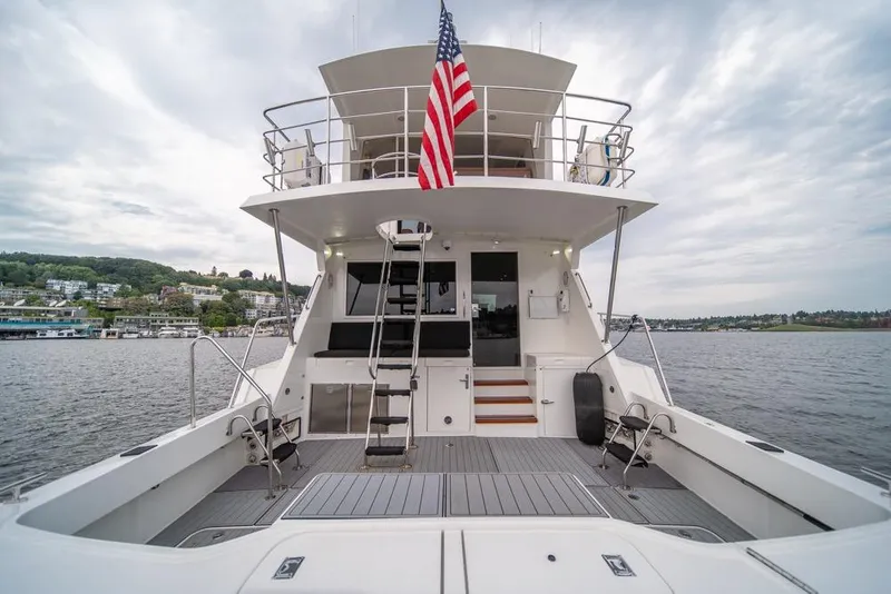 Slide: The Image of 1988 Hatteras 65 Sportfish yacht with American flag, docked on a scenic waterfront. - 38