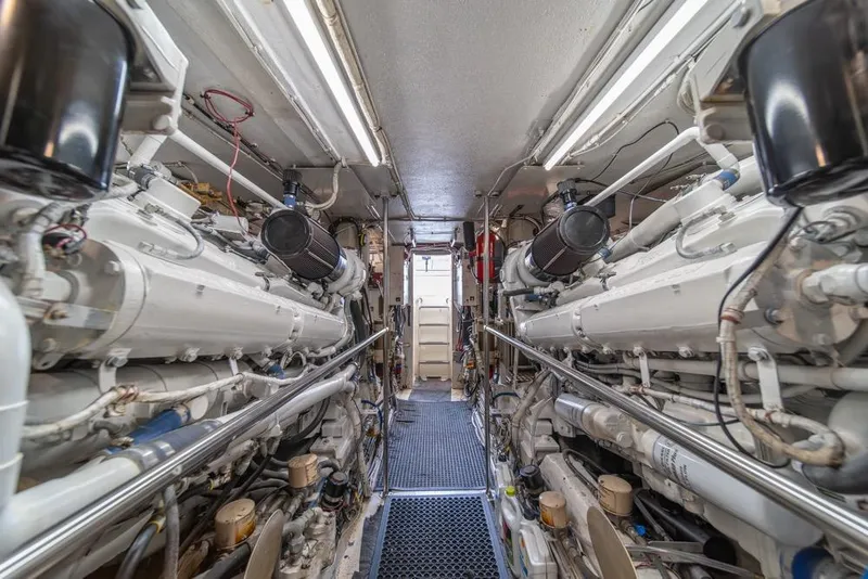 Slide: The Image of Engine room of a 1988 Hatteras 65 Sportfish yacht, featuring dual engines and intricate piping. - 48